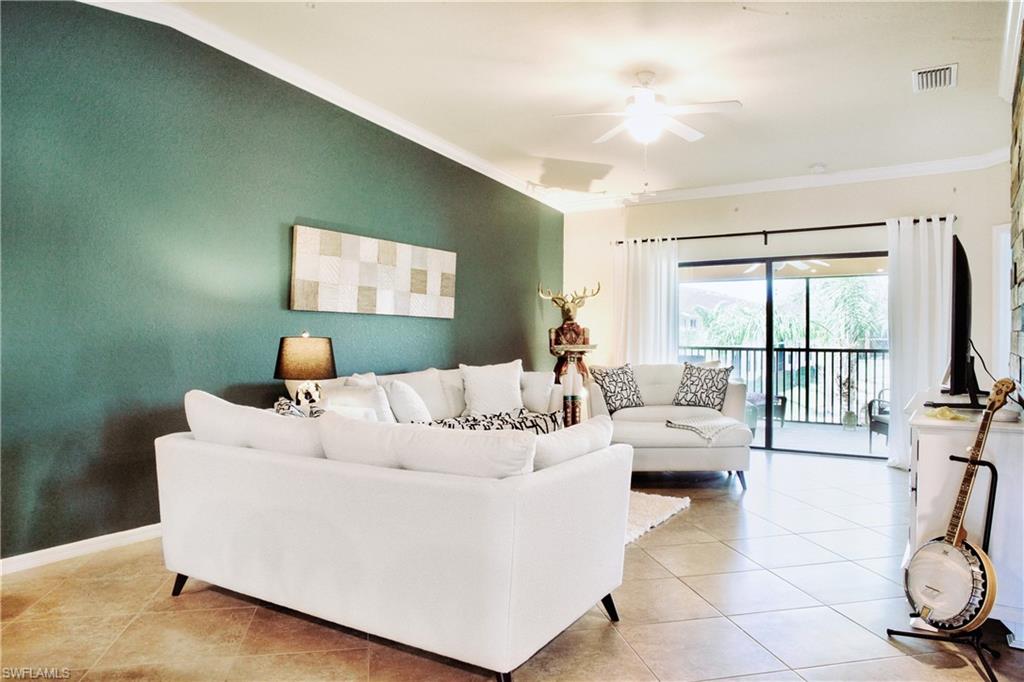 Spacious room featuring tile flooring, a ceiling fan, crown molding, and sliding glass doors opening to an outdoor screened area