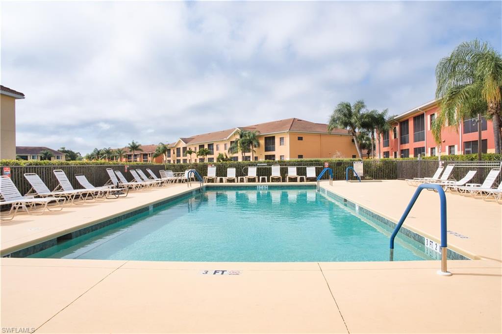 Expansive outdoor swimming pool with integrated entry handrails, surrounded by a large deck area and lounge seating