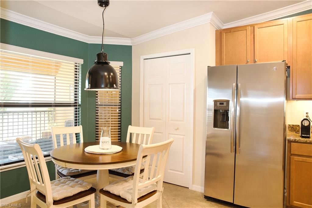 Built-in stainless steel refrigerator, wood-finish cabinetry, granite-style countertops, crown molding, and a pendant light fixture