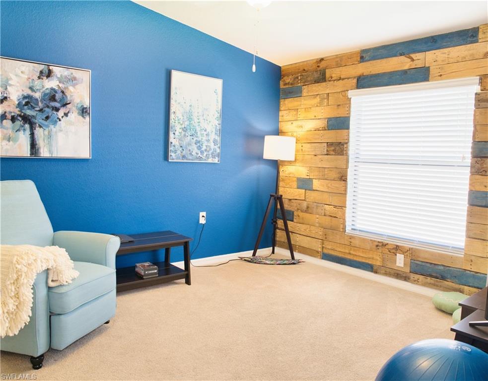 Carpeted flooring, accent wall with wood paneling, painted accent wall, window with blinds, ceiling fan