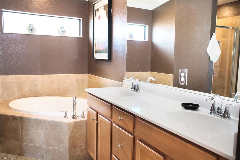 Dual vanity with integrated sinks, light wood-finish cabinetry, and a large wall-mounted mirror