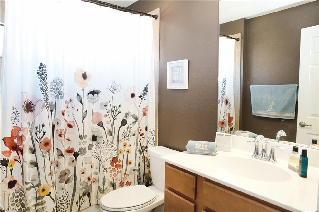 Bathroom featuring a single-sink vanity with wood-finish cabinetry, a white countertop, and a toilet