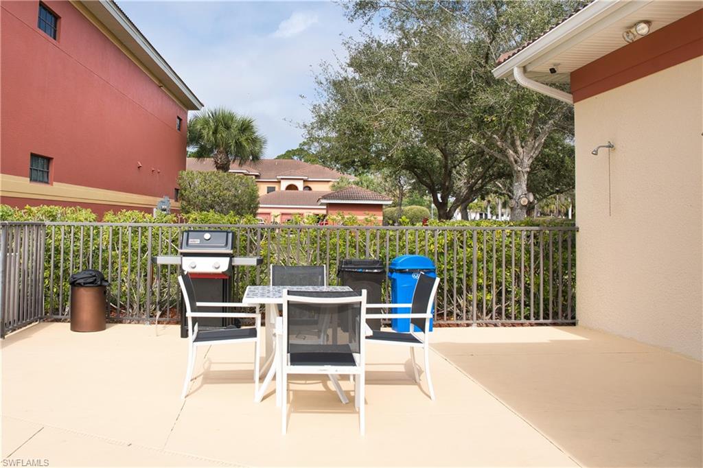 Expansive outdoor patio featuring a neutral-toned concrete surface, metal fencing, and a built-in outdoor shower