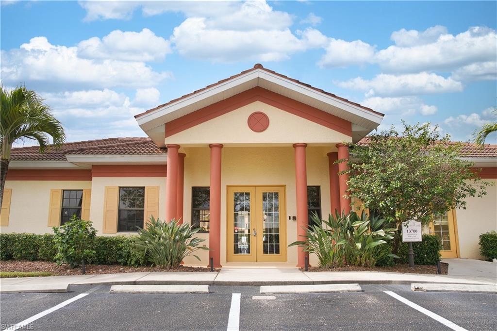 Tiled hip roof, stucco exterior, covered entry with columns, double glass-paneled entry doors, and mature landscaping