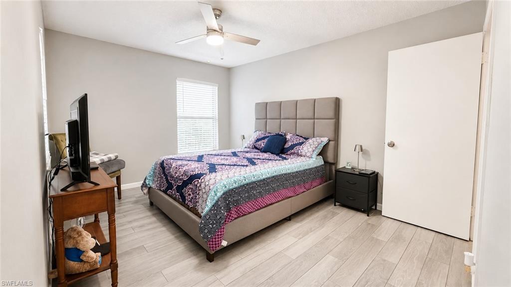 Ceiling fan with integrated lighting, wood-finish flooring, and a window with blinds