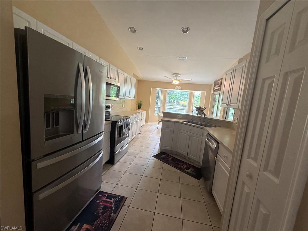 Kitchen featuring tile flooring, stainless steel appliances, white cabinetry, and recessed lighting