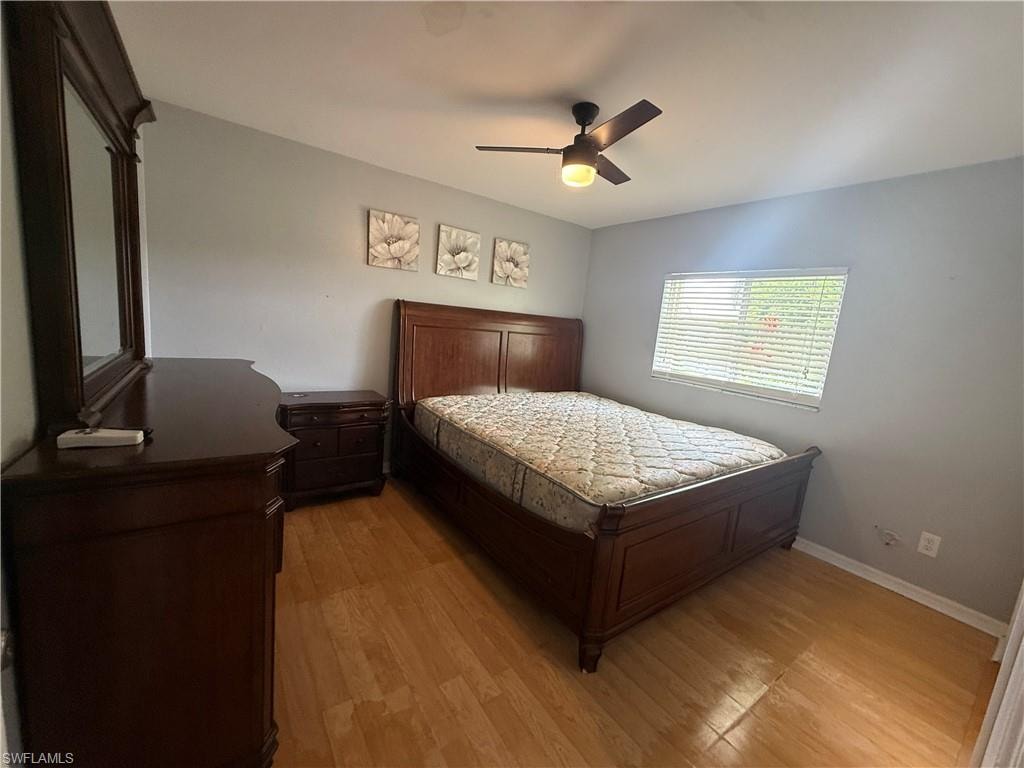 Wood-finish flooring throughout, ceiling fan with integrated lighting, and a window with horizontal blinds