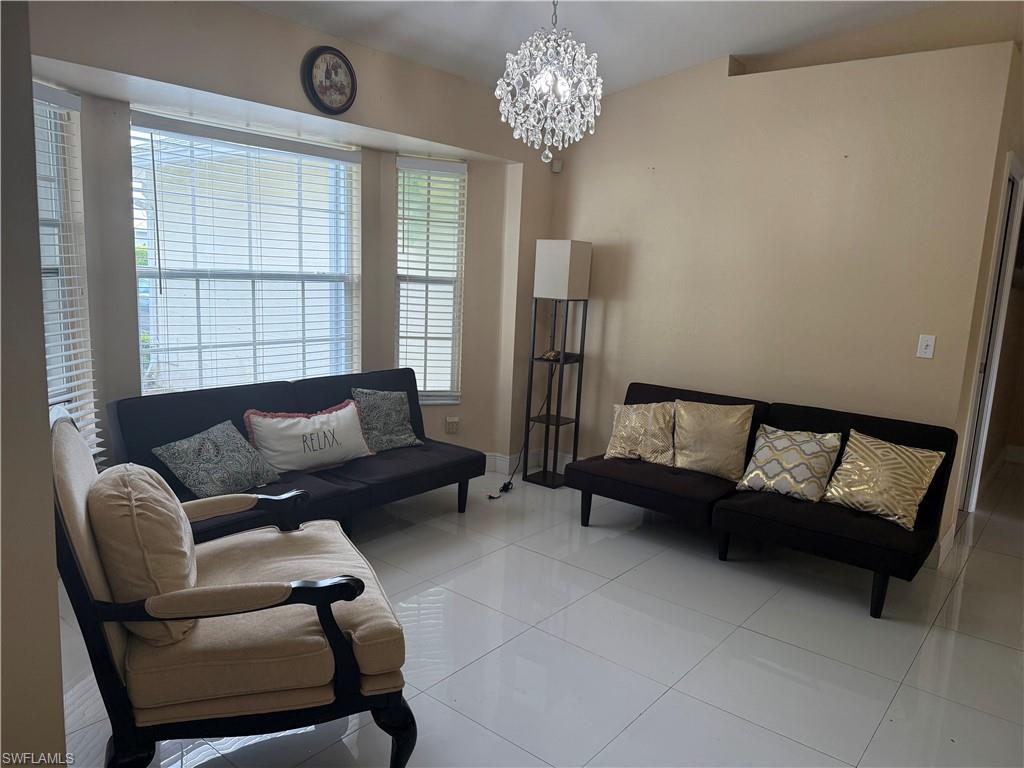 Recessed bay window, vaulted ceiling, white tile flooring, and a crystal chandelier