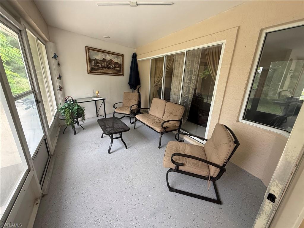 Enclosed sunroom featuring multiple large windows, textured wall finish, sliding glass doors, and a light-colored speckled floor