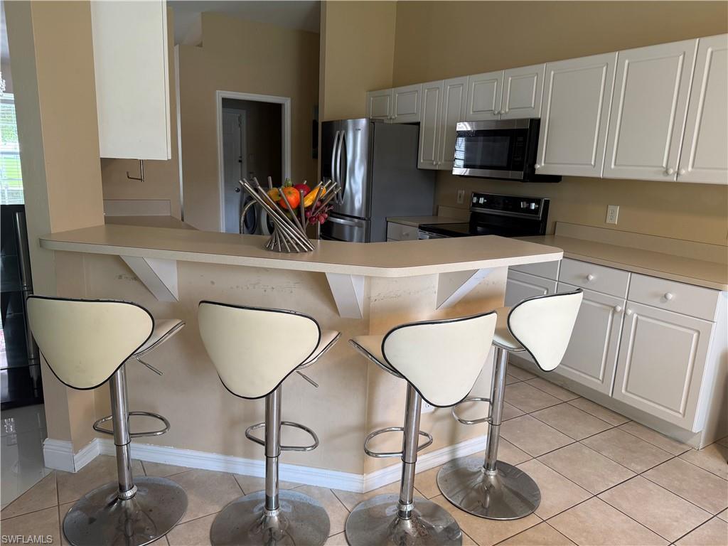 Kitchen featuring white cabinetry, light-toned countertops, stainless steel appliances, and tiled flooring