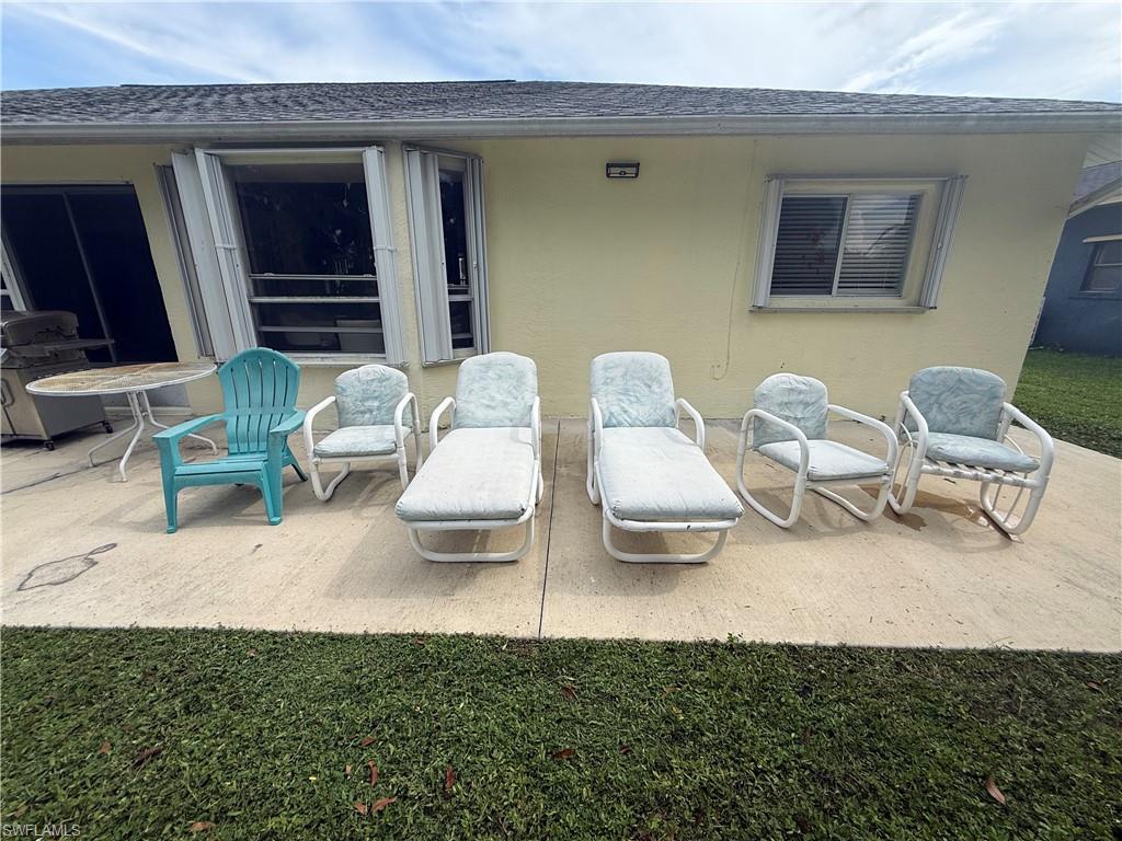 Poured concrete patio with a stucco exterior, multiple windows, and a dark shingle roof