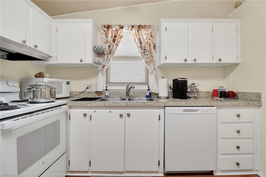 Kitchen featuring white cabinetry, a built-in dishwasher, an integrated sink, granite-look countertops, and an electric range with an overhead exhaust fan