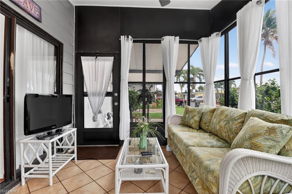 Screened room featuring full-height windows, tile flooring, and a ceiling fan