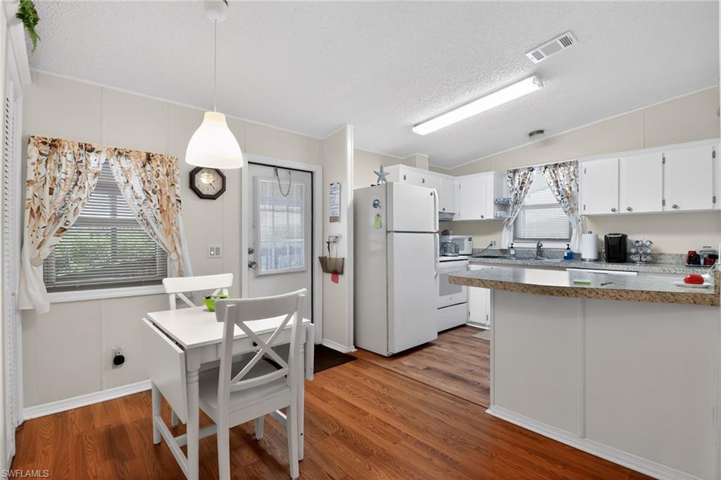 Kitchen featuring wood-finish flooring, white cabinetry, and light-toned countertops