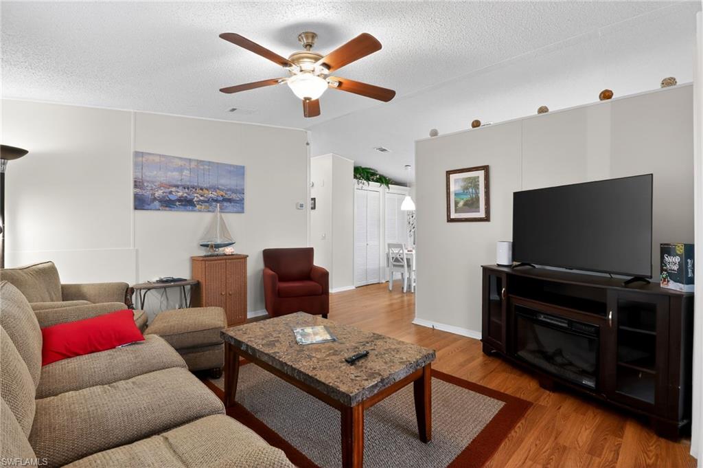 Living area featuring wood-finish flooring, a ceiling fan with integrated lighting, and neutral wall tones