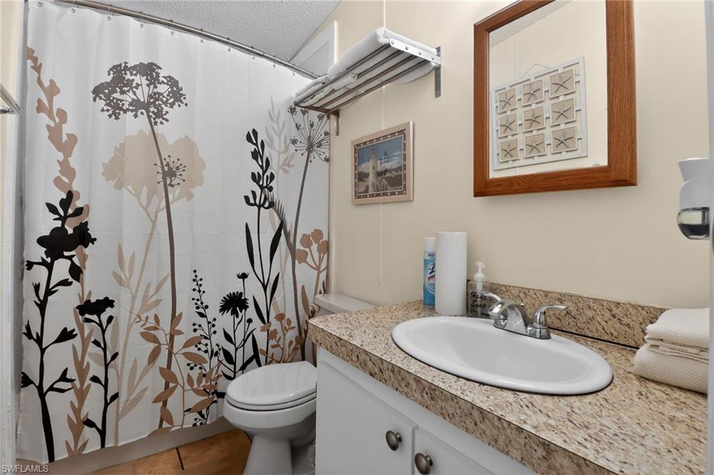 Bathroom featuring a vanity with an oval sink, speckled countertop, and white cabinetry