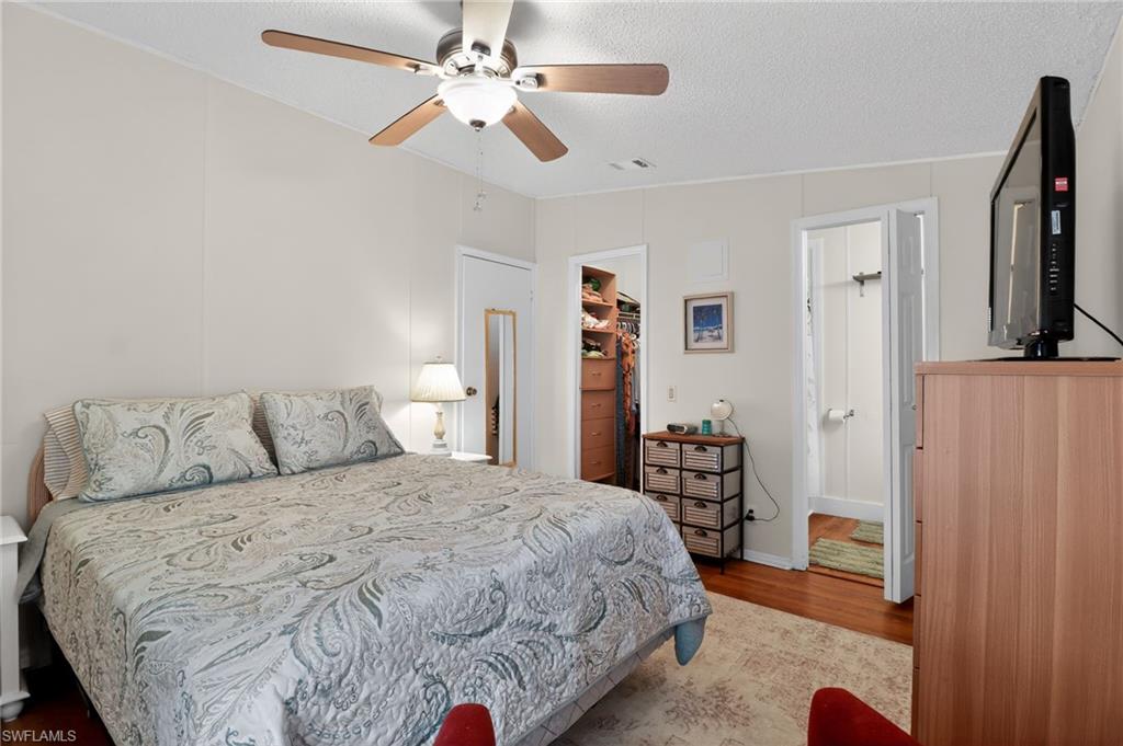 Bedroom featuring wood-finish flooring, a ceiling fan with integrated lighting, and multiple interior doorways