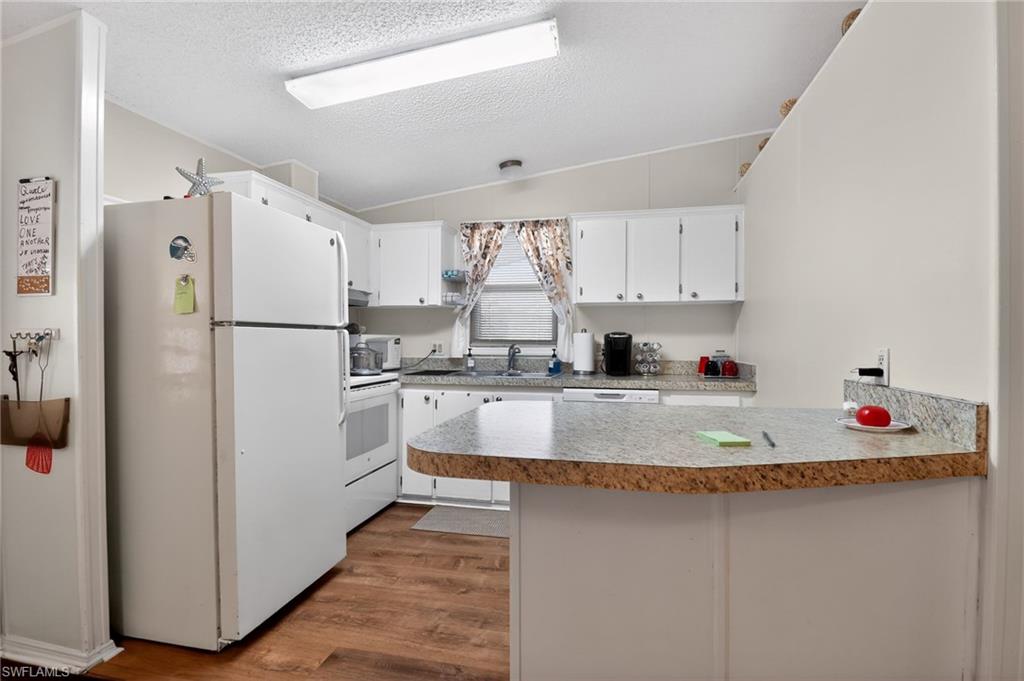 Kitchen featuring white cabinetry, wood-finish flooring, and a breakfast bar with a granite-style countertop