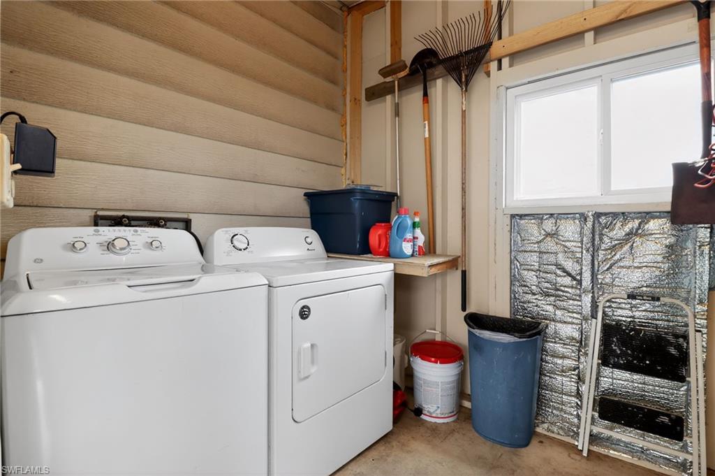Dedicated laundry area featuring a white washing machine and dryer, a mounted wood shelf, and a window providing natural light
