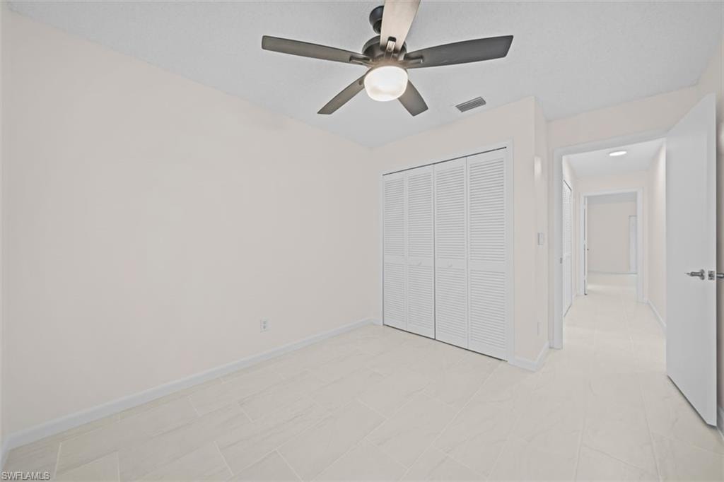 Ceiling fan with integrated lighting, louvered bi-fold closet doors, and light-toned tile flooring