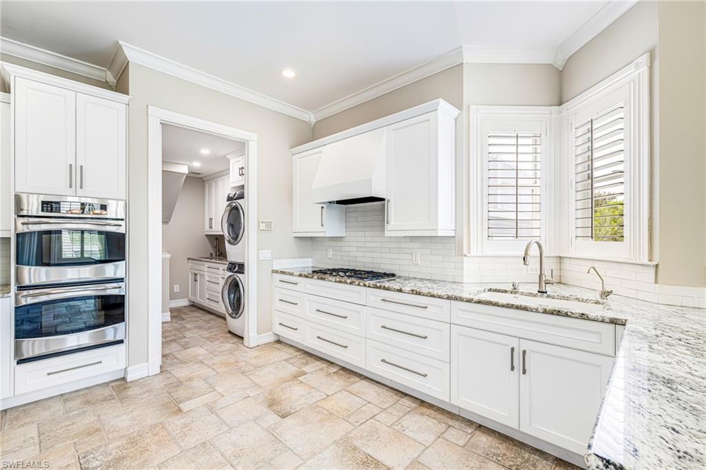 White cabinetry with stainless steel hardware, built-in double oven, gas cooktop, subway tile backsplash, and light-toned tile flooring