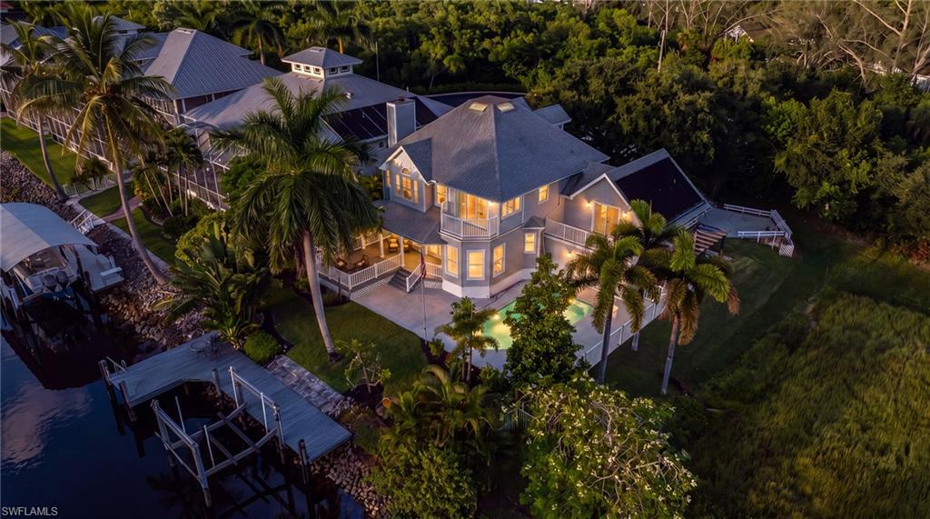 Waterfront property with a private dock, boat lift, and lush tropical landscaping
