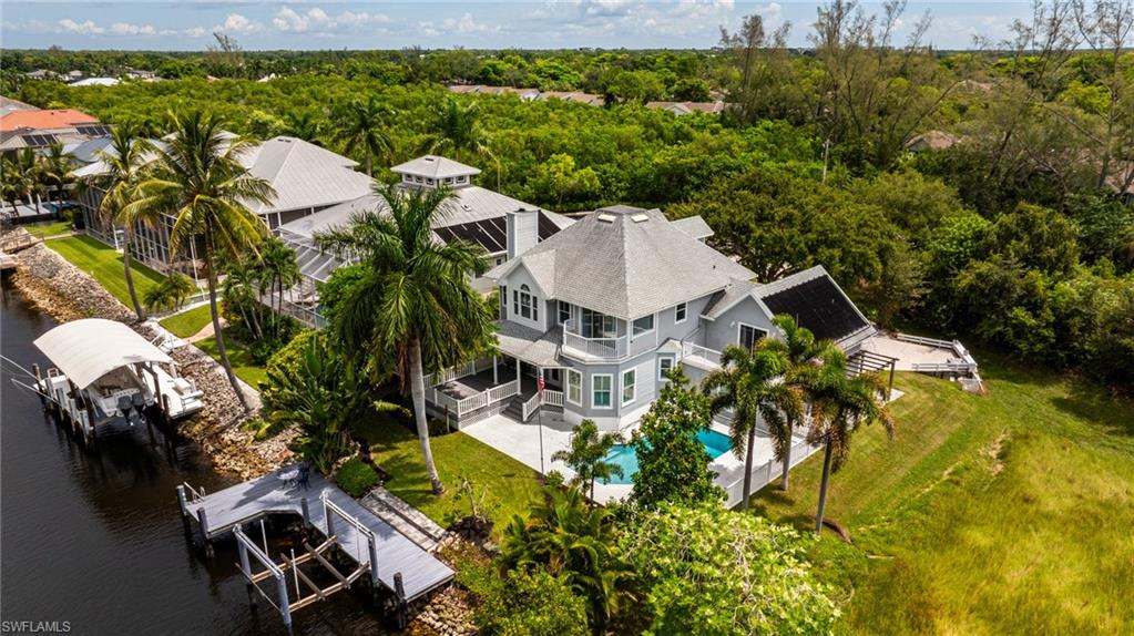 Gray multi-story exterior with multiple balconies, an in-ground swimming pool, and a private dock with a boat lift