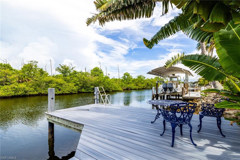 Composite wood dock with a boat lift, water access, and lush surrounding foliage