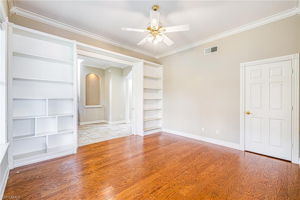 Hardwood flooring, built-in shelving, crown molding, ceiling fan, and six-panel interior door
