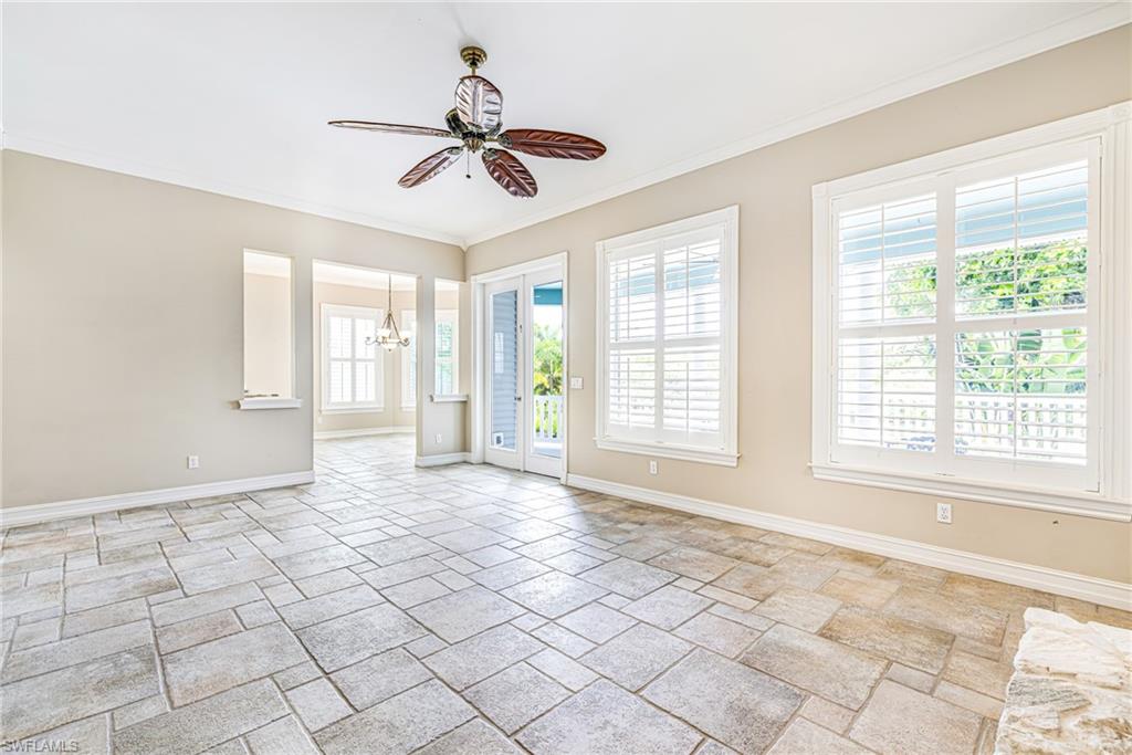Spacious room featuring large format tile flooring, crown molding, a decorative ceiling fan, and multiple windows with plantation shutters