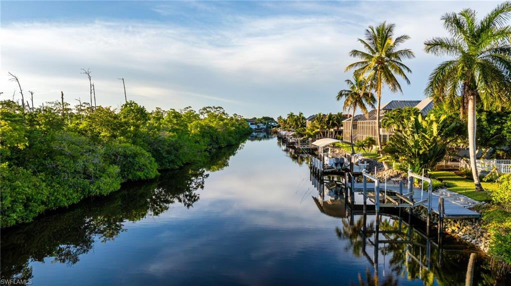 Waterfront property featuring multiple boat docks, tropical landscaping, and mature palm trees
