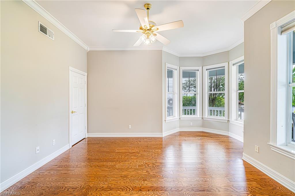 Hardwood flooring, crown molding, a bay window configuration, a ceiling fan, and painted walls