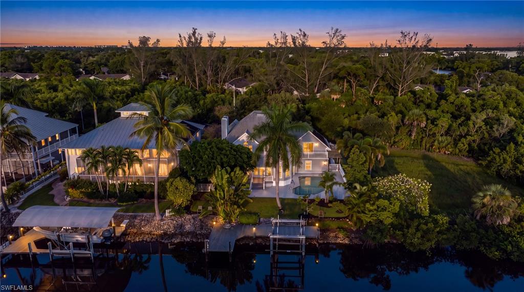 Waterfront property with boat lift, boat dock, and lush surrounding landscaping