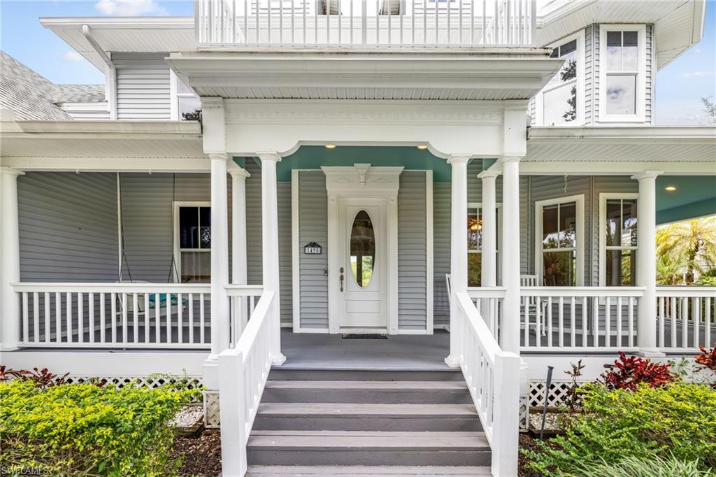 Covered porch with white railings, a white oval-lite entry door, and a light blue porch ceiling