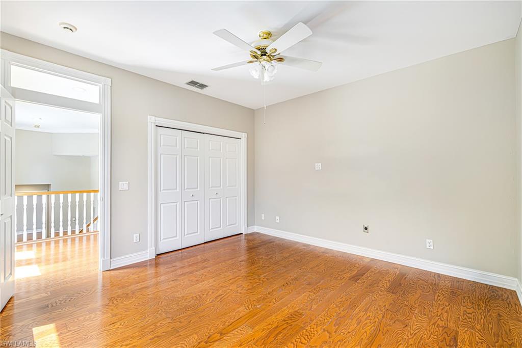 Hardwood flooring, ceiling fan with illumination, bi-fold closet doors, white trim, and neutral wall paint