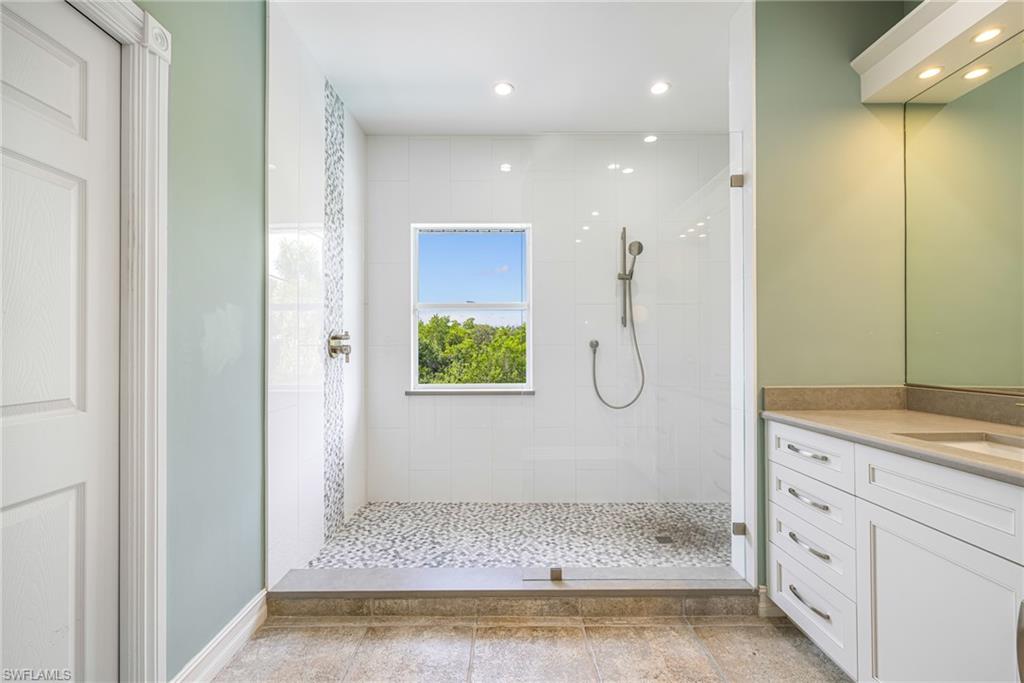 Spacious walk-in shower with pebble tile flooring and white wall tile
