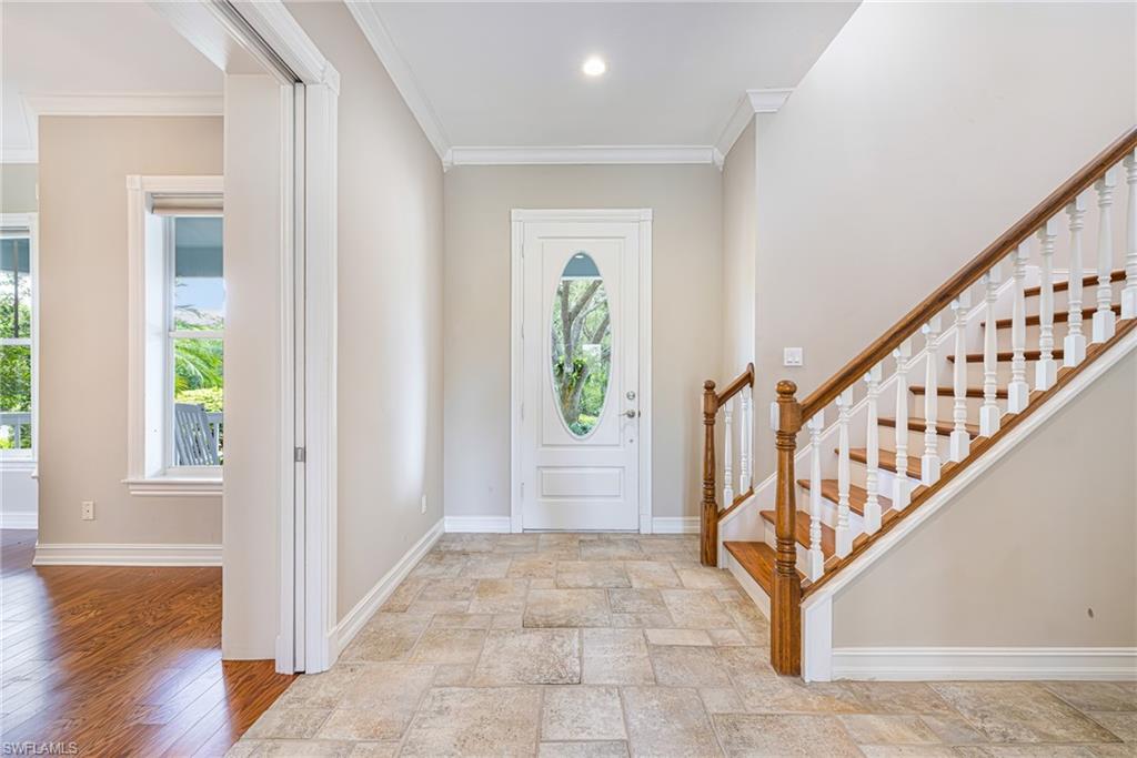 Foyer featuring tiled flooring, a wooden staircase with white balusters, and a front entry door with an oval glass insert
