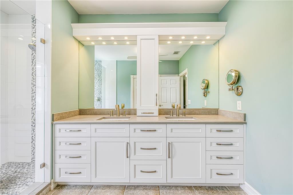 Dual vanity with integrated sinks and brushed nickel faucets, set against a full-width mirror with overhead lighting