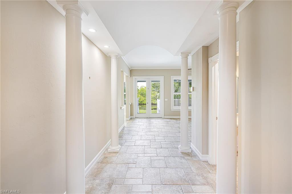 Hallway with columns, recessed lighting, and tile flooring