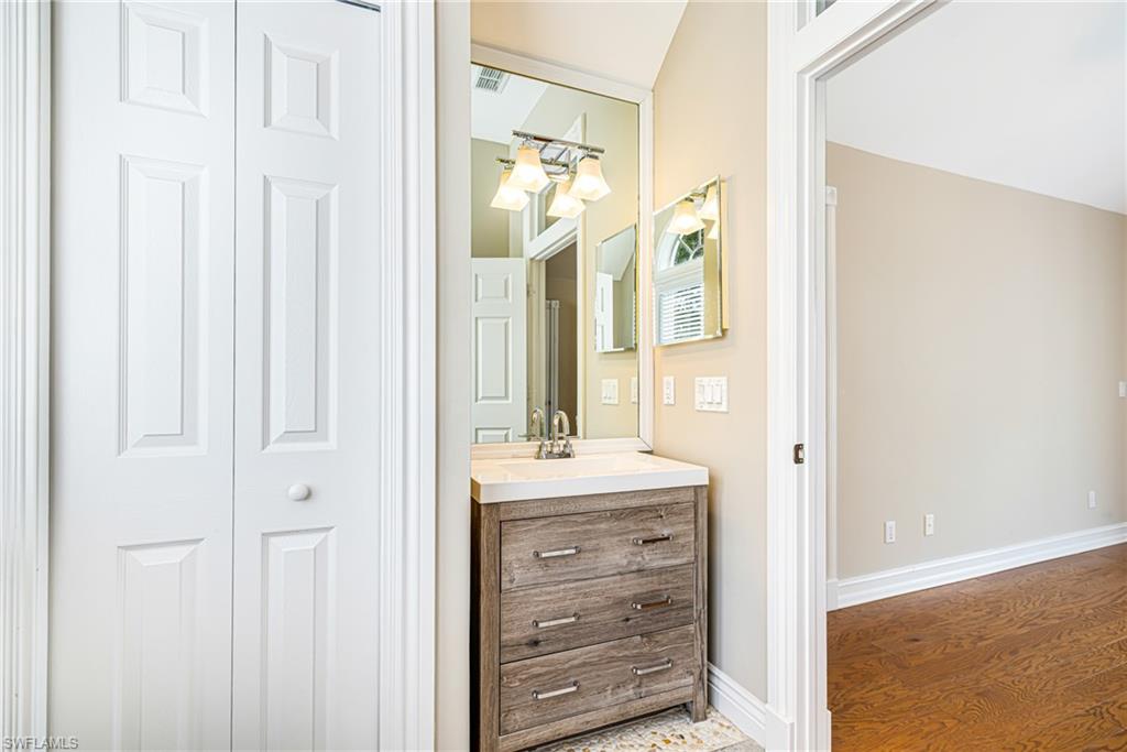 Built-in vanity with a stone countertop, undermount sink, and wall-mounted light fixture