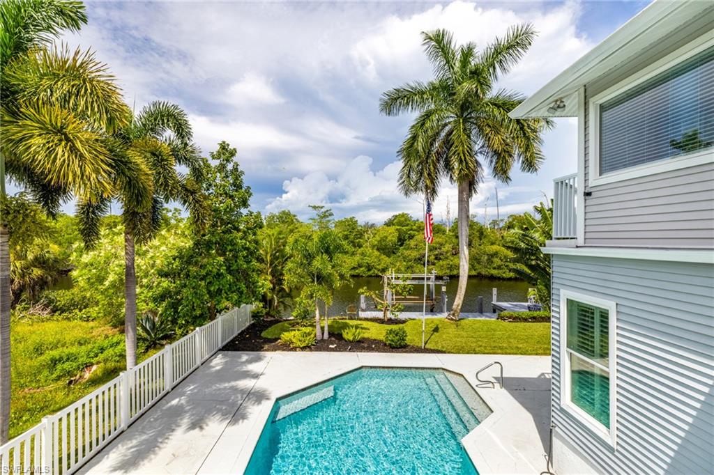 Outdoor swimming pool with integrated steps, surrounded by a white fence and a manicured lawn