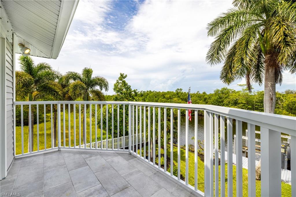 Balcony with light-toned rectangular tile flooring, white metal railing, and palm trees