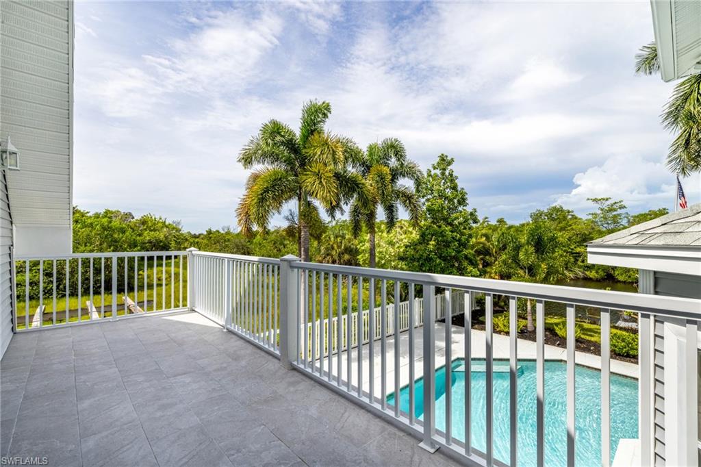 Upper-level balcony with tile flooring, white railing, and exterior wall sconce