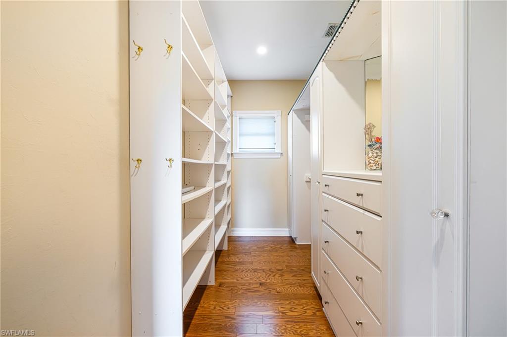 Custom built-in shelving, integrated dresser drawers, wood-finish flooring, recessed lighting, and a frosted window