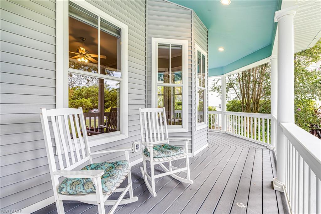 Expansive front porch featuring gray wood-finish decking, white railings, and a light blue ceiling