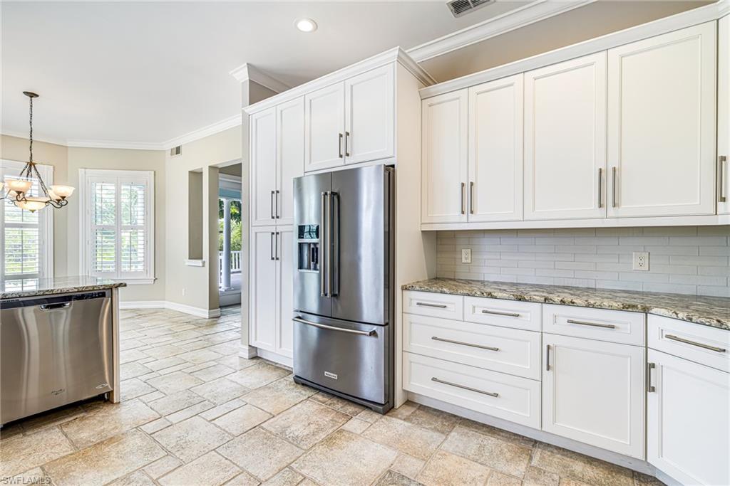 White shaker cabinetry, stainless steel appliances, speckled stone countertops, subway tile backsplash, and large format stone tile flooring