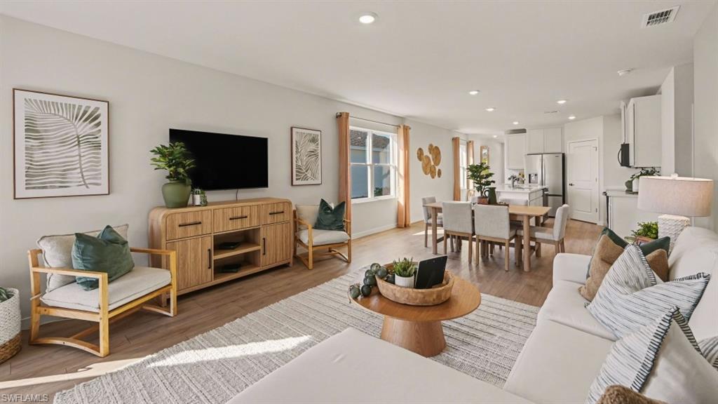 Open-concept living area featuring wood-finish flooring, recessed lighting, and ample natural light from multiple windows
