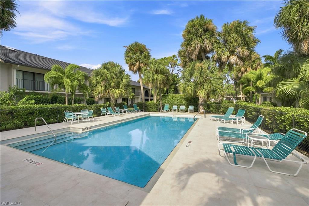 Community swimming pool featuring a concrete deck and lush landscaping