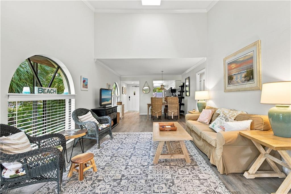 Vaulted ceiling with a skylight, arched window with horizontal blinds, wood-finish flooring, and recessed ceiling lights