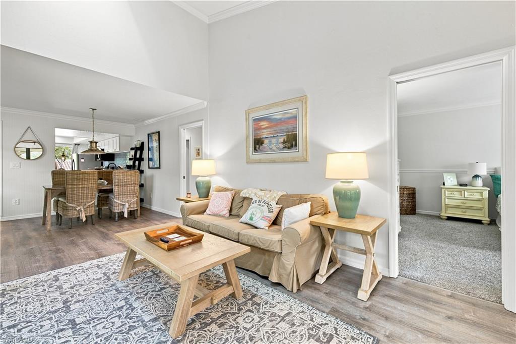 Vaulted ceiling with crown molding, wood-finish flooring, recessed lighting, and an open concept dining area